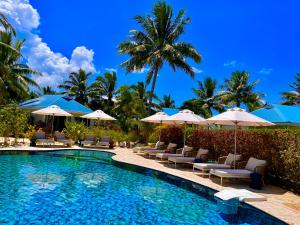 a swimming pool with chairs and umbrellas at Opoa Beach Hotel in Opoa