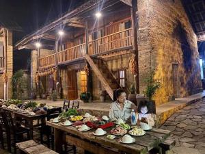 a woman and child sitting at a table with food at homestay bongbang in Ha Giang
