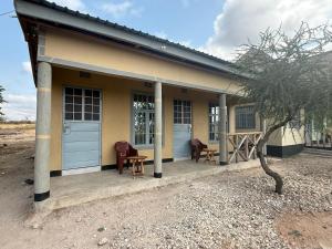 a small yellow house with two chairs and a table at Oltare Safari Homestay in Makuyuni