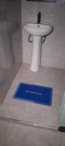 a bathroom with a white sink and a blue scale at Oltare Safari Homestay in Makuyuni
