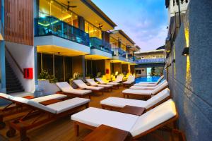 a hotel patio with lounge chairs and a swimming pool at Lighthouse Hotel in Gili Trawangan
