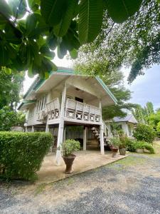 a white house with a porch and some plants at Baan Suan Yensabai @Ayutthaya in Phra Nakhon Si Ayutthaya