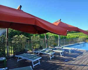 a patio with a large red umbrella and a pool at Tra... Monti E Vigne in La Morra