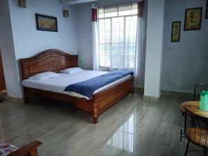 a bedroom with a bed in a room with a window at Vibgyor Hotel in Cherrapunji +20 photos