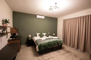 a bedroom with a bed with a green wall at Weavers Nest Guesthouse in Modimolle
