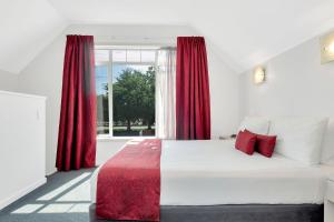 a bedroom with a large bed with red curtains at Matamata Central Motel in Matamata