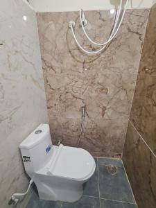 a white toilet in a bathroom with a marble wall at Kalpavrukksha Luxury Service Apartment- Unit 4 - 1 BHK 2 King Size Cot Setup in Chikmagalūr +4 photos