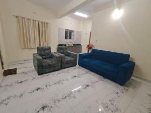 a living room with a blue couch and two chairs at Kalpavrukksha Luxury Service Apartment- Unit 4 - 1 BHK 2 King Size Cot Setup in Chikmagalūr