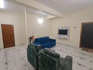 a living room with a couch and a blue chair at Kalpavrukksha Luxury Service Apartment- Unit 4 - 1 BHK 2 King Size Cot Setup in Chikmagalūr