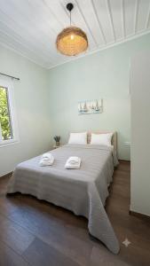 a white bedroom with a large bed with two towels on it at Secret-Garden in Chios