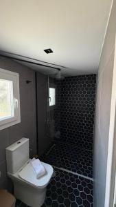 a bathroom with a toilet and a shower with black tiles at Secret-Garden in Chios