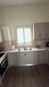 a kitchen with white cabinets and a sink and two windows at Secret-Garden in Chios +1 photo