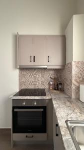 a kitchen with white cabinets and a stove and a sink at Secret-Garden in Chios