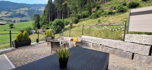 a patio with a table and chairs and a stone wall at Bijou Hollandia in Engelberg