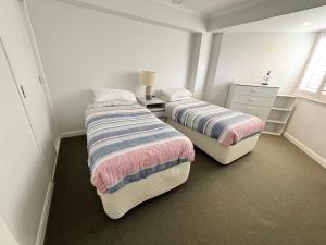 two twin beds in a room with a dresser at Ocean Shores Apartment 14 - Bring your own linen. in South West Rocks +13 photos