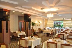 a restaurant with white tables and chairs and a chandelier at Othello Hotel in Mersin