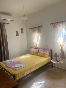 a bedroom with a bed with yellow sheets and two windows at Argoliki Thalassa in Myloi