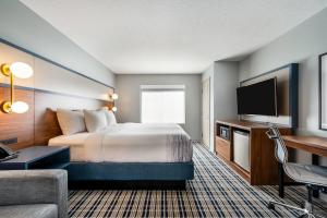 a hotel room with a bed and a flat screen tv at AmericInn by Wyndham Fairfield in Fairfield