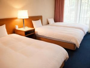 a hotel room with two beds and a lamp at Minami Hakone Villa in Kannami