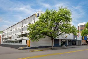 a large white building with a tree in front of it at Baymont by Wyndham Great Falls City Center in Great Falls