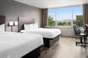 a hotel room with two beds and a desk and a chair at Baymont by Wyndham Great Falls City Center in Great Falls +48 photos