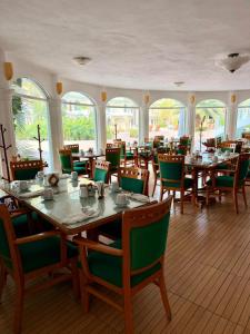 ein Esszimmer mit Tischen, Stühlen und Fenstern in der Unterkunft Hotel Costa Azul in Acapulco