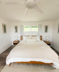 a white bedroom with a large white bed with two lamps at Kona Kai Ocean View Suite in Kailua-Kona