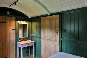 a bedroom with green walls and a bed with a mirror at Hornbeam Holt in Broadway