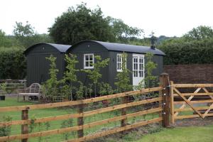 a black shed in a garden with a fence at Hornbeam Holt in Broadway
