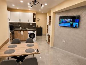 a kitchen with a table and a tv on a wall at Apartment The Garden Ruse, Private Garden & Free Parking in Ruse