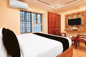 a bedroom with a white bed and a television at Collection O Tennati Park Vizag Beach Formerly B Square Villa in Visakhapatnam +20 photos