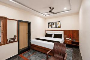 a bedroom with a bed and a chair in it at Collection O Tennati Park Vizag Beach Formerly B Square Villa in Visakhapatnam