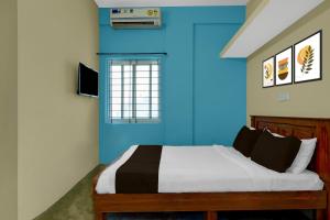 a bedroom with a bed with a blue wall at Hotel O Abbigere Lakeview Bangalore Formerly Shree Venkateshwar Atithi Comforts in Chik Bānavar