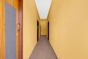 a hallway with yellow walls and a long corridor at Hotel O Abbigere Lakeview Bangalore Formerly Shree Venkateshwar Atithi Comforts in Chik Bānavar