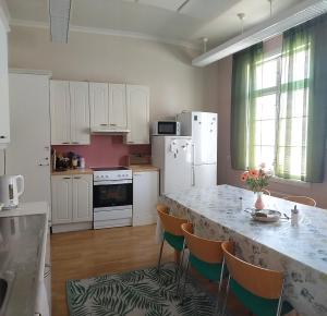 a kitchen with a table with chairs and a white refrigerator at Hostelli Marja in Mikkeli