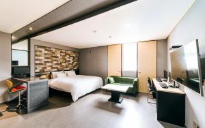 a hotel room with a bed and a desk with a computer at Hotel Ssome Jeongkwan in Busan