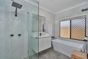 a white bathroom with a tub and a glass shower at Villa Aura - Private Pool - Lakefront & Near Beach in Trinity Beach