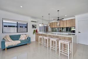 a kitchen with a blue couch and a bar with stools at Villa Aura - Private Pool - Lakefront & Near Beach in Trinity Beach