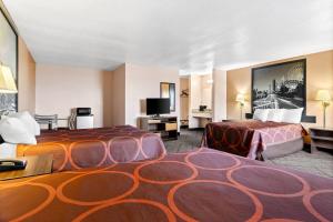 ein Hotelzimmer mit zwei Betten und einem Flachbildfernseher in der Unterkunft Super 8 by Wyndham Bourbonnais/Kankakee Area in Bourbonnais