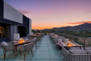 a restaurant with tables and chairs on a balcony at sunset at Keys Lite by Lemon Tree Hotels, Ajmer in Ajmer