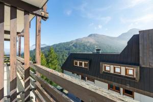 a house with a black roof with mountains in the background at Appartamento Alpine Suite - Happy Rentals in Sestriere