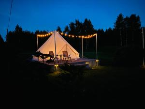 una tenda con due sedie e luci di notte di Eglīši a Kalnamuiža