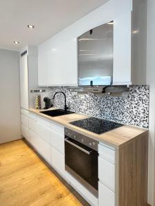 a kitchen with white cabinets and a stove top oven at Stille leilighet med topp beliggenhet i Tromsø sentrum in Tromsø