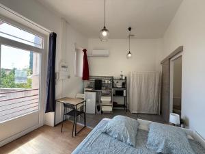 a bedroom with a bed and a desk and a window at LA MAISON D'ANTONIN 2 in Nîmes