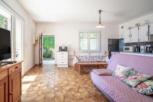 a living room with a purple couch and a kitchen at Maison Vacances Mer in Bages