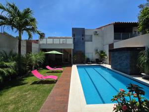 a swimming pool with two pink chairs and a house at Tourist House in Santa Cruz de la Sierra