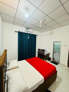 a bedroom with a red and white bed and a desk at G Lake Guest House in Mahiyangana +7 photos
