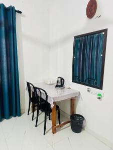 a table with chairs and a computer monitor on a wall at G Lake Guest House in Mahiyangana