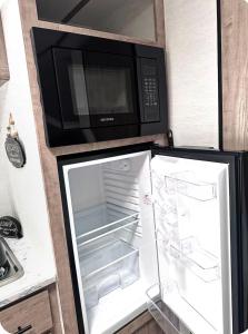 a refrigerator with its door open with a microwave at Cozy RV tiny home in Fort Lauderdale