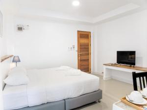 a white bedroom with a bed and a desk at Grand Sattahip Hotel in Sattahip